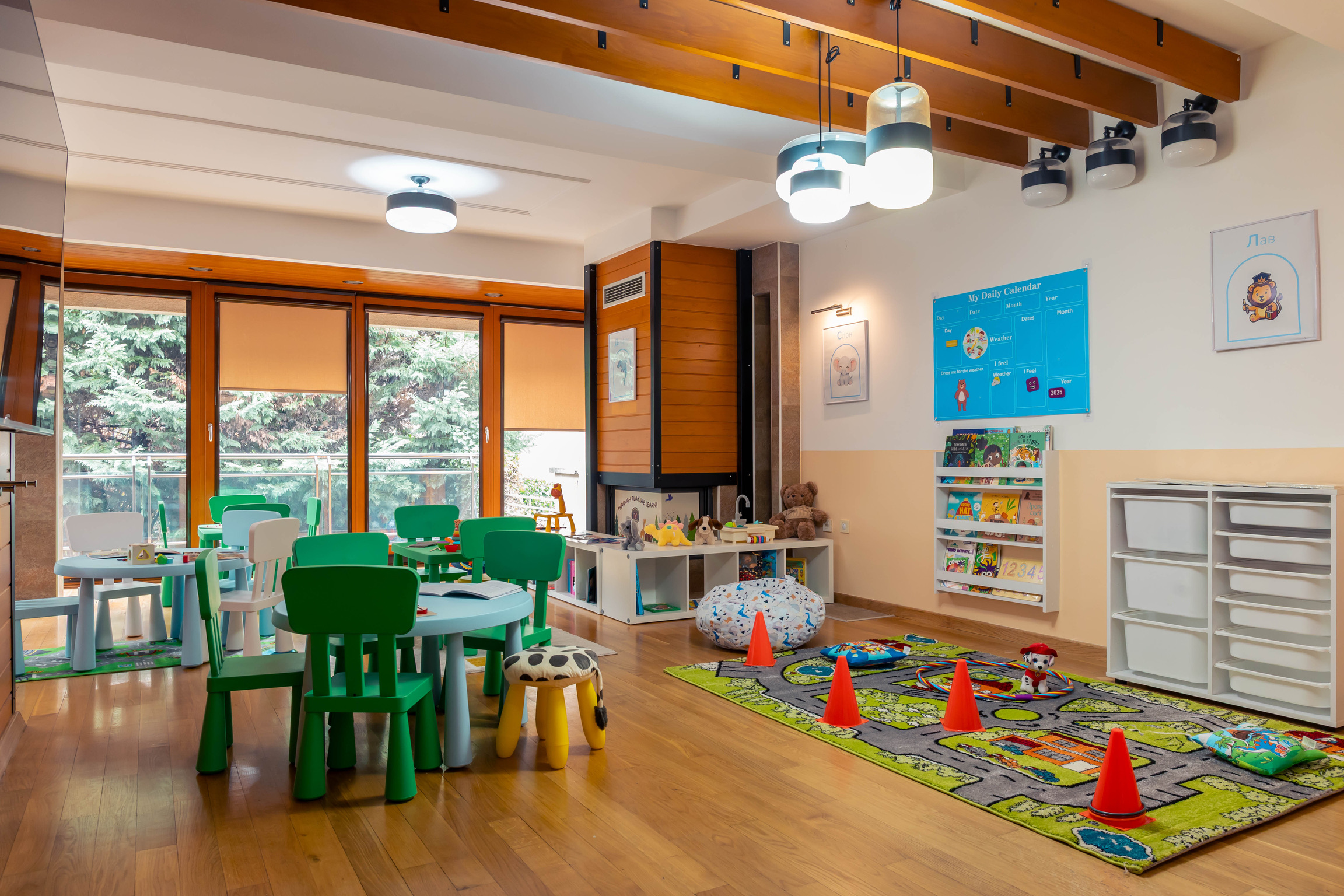 Sunlit main classroom with play areas and a road-print rug
